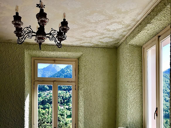 уютная спальня с панорамными окнами и видом на горы, светлые стены с текстурой, стильная люстра и мягкое постельное белье, создающее уют и комфорт в премиальной недвижимости Треви Элит.