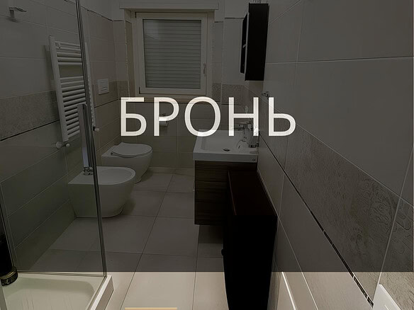 Современная ванная комната с душевой кабиной, унитазом и умывальником в светлом стиле, дизайнерский интерьер, богатая отделка керамической плиткой, окна для естественного освещения, оборудование высокого класса.