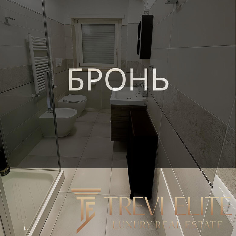 Современная ванная комната с душевой кабиной, унитазом и умывальником в светлом стиле, дизайнерский интерьер, богатая отделка керамической плиткой, окна для естественного освещения, оборудование высокого класса.