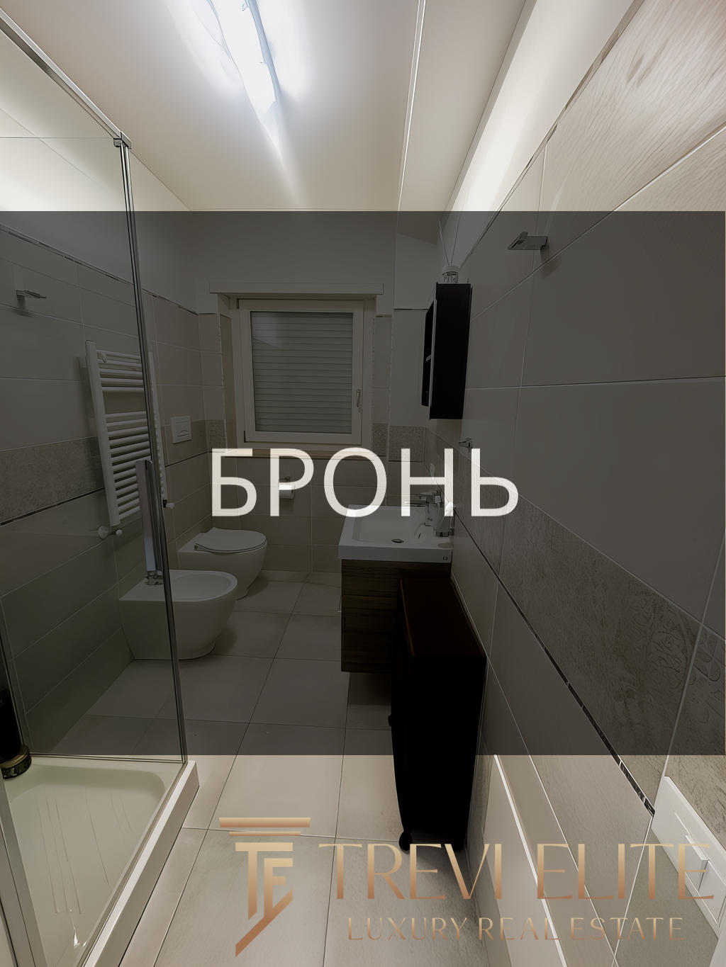 Современная ванная комната с душевой кабиной, унитазом и умывальником в светлом стиле, дизайнерский интерьер, богатая отделка керамической плиткой, окна для естественного освещения, оборудование высокого класса.