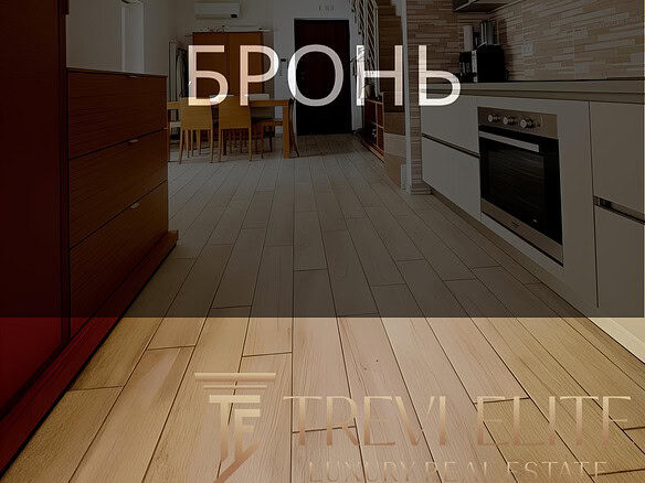 Комнатное интерьерное изображение современной кухни с деревянными полами и встроенной техникой, идеальное оформление для презентации элитной недвижимости от Треви Элит.