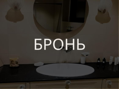 Элегантный интерьер ванной комнаты с зеркальным круглым зеркалом, современным светильником, белым умывальником и эстетичной мебелью, создающей уютную и стильную атмосферу.