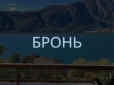 Бронирование пейзажного вида на озеро и горы с балкона с деревянным поручнем и уютным креслом.