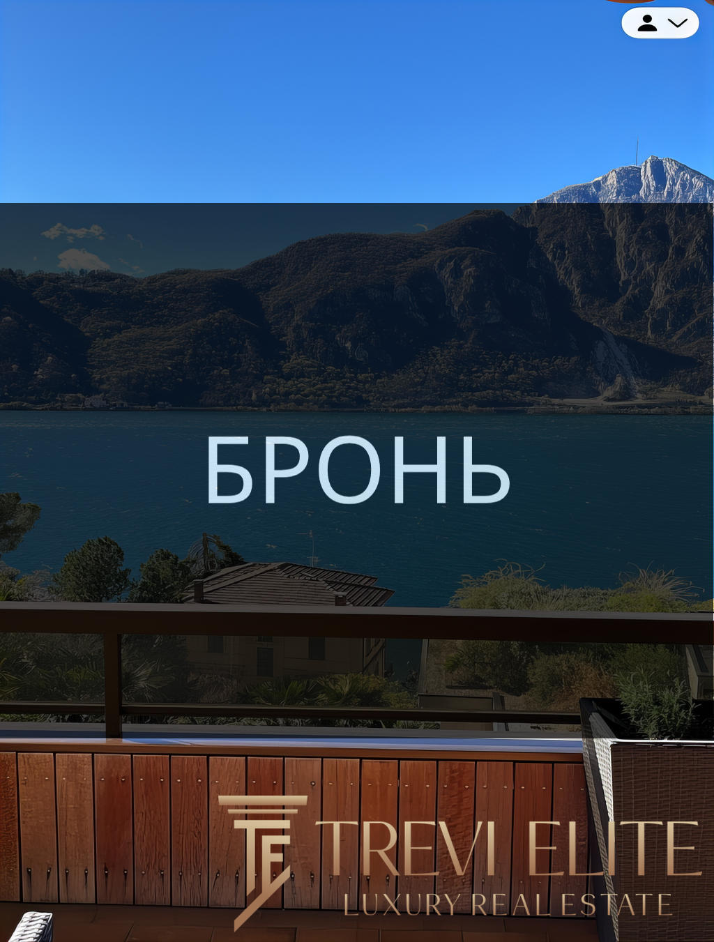 Бронирование пейзажного вида на озеро и горы с балкона с деревянным поручнем и уютным креслом.