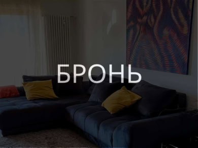 Высокотехнологичный дизайн гостиной с современной мебелью и ярким абстрактным искусством на стене. Просторное и уютное помещение с мягким ковром и стильными подушками.
