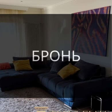 Высокотехнологичный дизайн гостиной с современной мебелью и ярким абстрактным искусством на стене. Просторное и уютное помещение с мягким ковром и стильными подушками.
