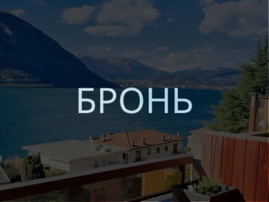 вид на озеро и горы с балкона с деревянным настилом, уютной мебелью и цветущими растениями, панорамный вид на природу и спокойствие, фото демонстрирует роскошные апартаменты у воды, агентство недвижимости Треви Элит.