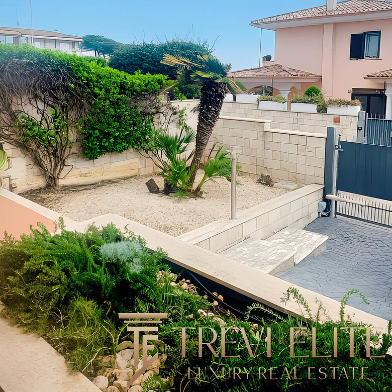 Улица с ухоженным садом и пальмами рядом с частным домом в солнечную погоду.