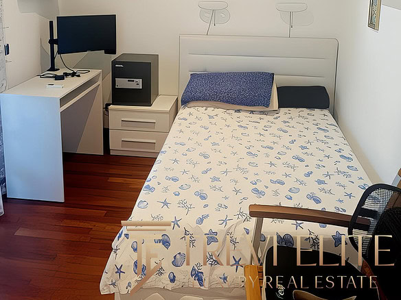 Стильная комната в квартире с белыми стенами, украшенная картинами на морскую тему, с удобной кроватью, письменным столом и современным оборудованием для работы и отдыха.