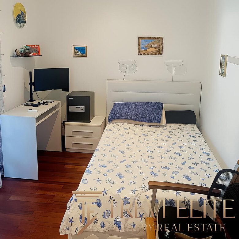 Стильная комната в квартире с белыми стенами, украшенная картинами на морскую тему, с удобной кроватью, письменным столом и современным оборудованием для работы и отдыха.