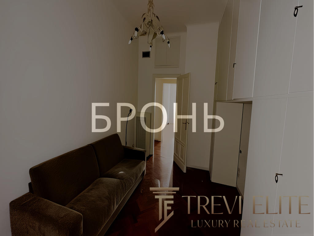 Короткий, уютный коридор с тёмным диваном и встроенными шкафами, светлая стена и дверь, светильник сверху, в минималистском стиле, интерьер современный, комфортный, пространство организовано эргономично, подходит для комфортного проживания.