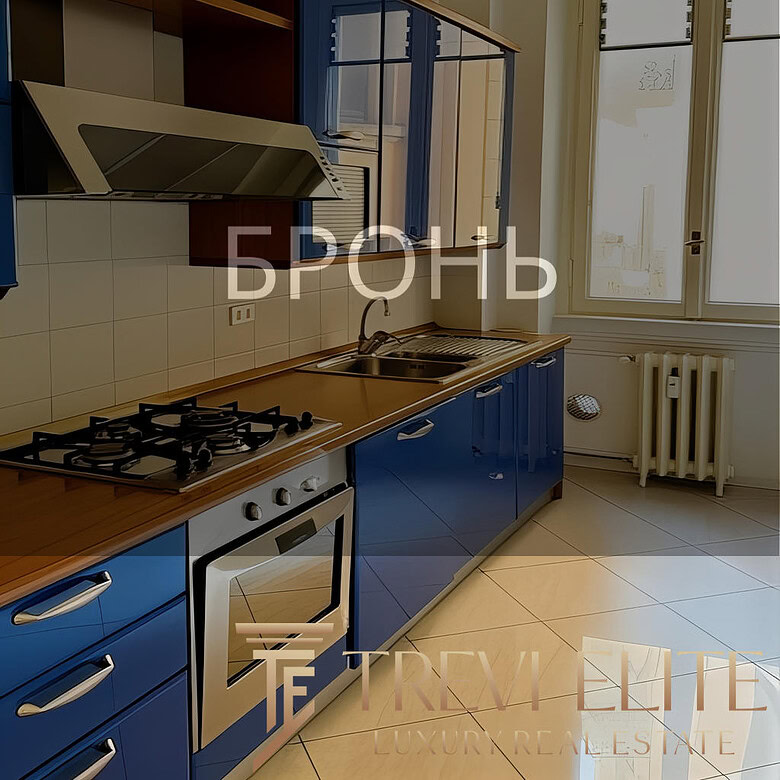 Газовая плита, синие кухонные шкафы и окно с видом на улицу в современной кухне. Просторная и светлая кухня с удобным дизайном, идеально подходит для комфортного проживания.