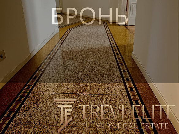 Высококачественный интерьер коридора в современном жилом доме. Теплое освещение, гладкие стены и укороченный ковровый дорожка создают уютную атмосферу. Идеальное изображение для риелторского агентства Треви Элит.