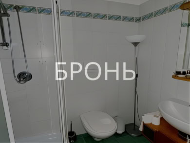 солнечный интерьер ванной комнаты с душевой кабиной, унитазом и раковиной, зеленым полом и декоративной плиткой, современное уютное пространство в частном доме, комфортное жилье.