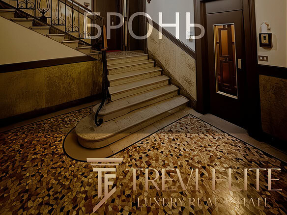 Высокий этаж жилого дома с элегантной лестницей, мраморными ступенями и художественной отделкой стен в классическом стиле. Идеальное пространство для проживания или аренды с уютной атмосферой и продуманной планировкой.