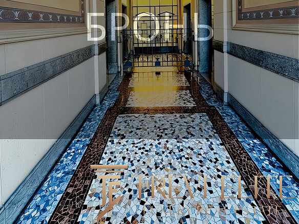 Элегантный коридор в роскошном жилом комплексе с витражными окнами и декоративной мозаикой на полу, создающий атмосферу уюта и статуса.