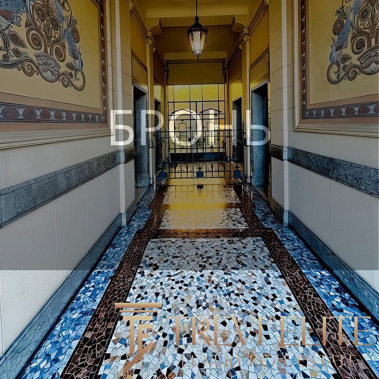 Элегантный коридор в роскошном жилом комплексе с витражными окнами и декоративной мозаикой на полу, создающий атмосферу уюта и статуса.