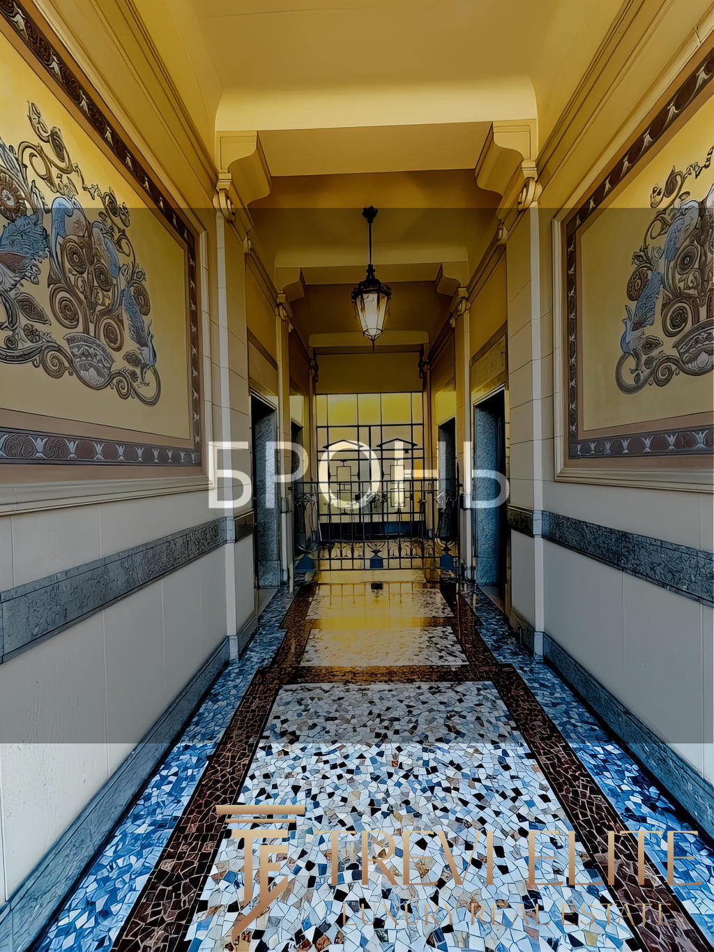 Элегантный коридор в роскошном жилом комплексе с витражными окнами и декоративной мозаикой на полу, создающий атмосферу уюта и статуса.