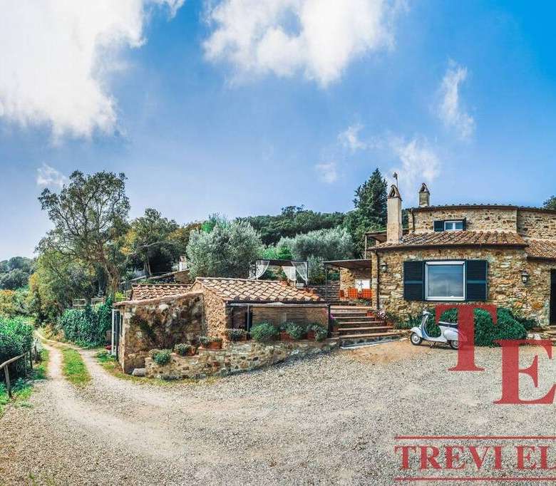 Уединенный роскошный дом из камня на холме с видом на природу, окруженный деревьями, с уютной террасой и зеленым садом для элитного отдыха.