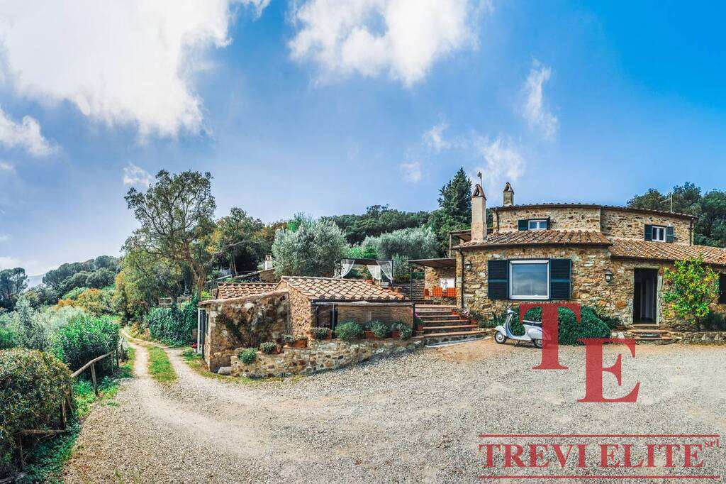 Уединенный роскошный дом из камня на холме с видом на природу, окруженный деревьями, с уютной террасой и зеленым садом для элитного отдыха.