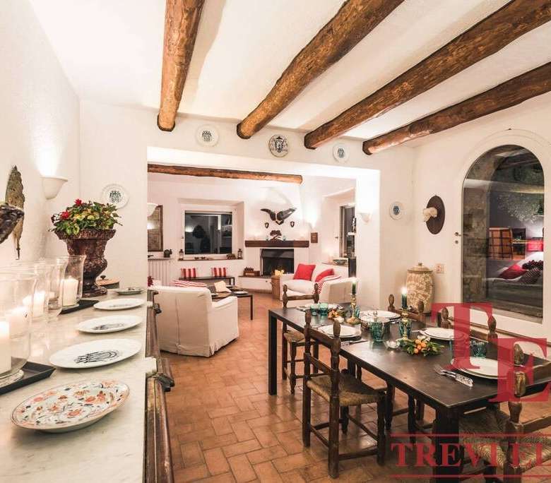 Роскошный интерьер загородного дома с белыми стенами, деревянными балками и уютной обстановкой для элитной недвижимости.