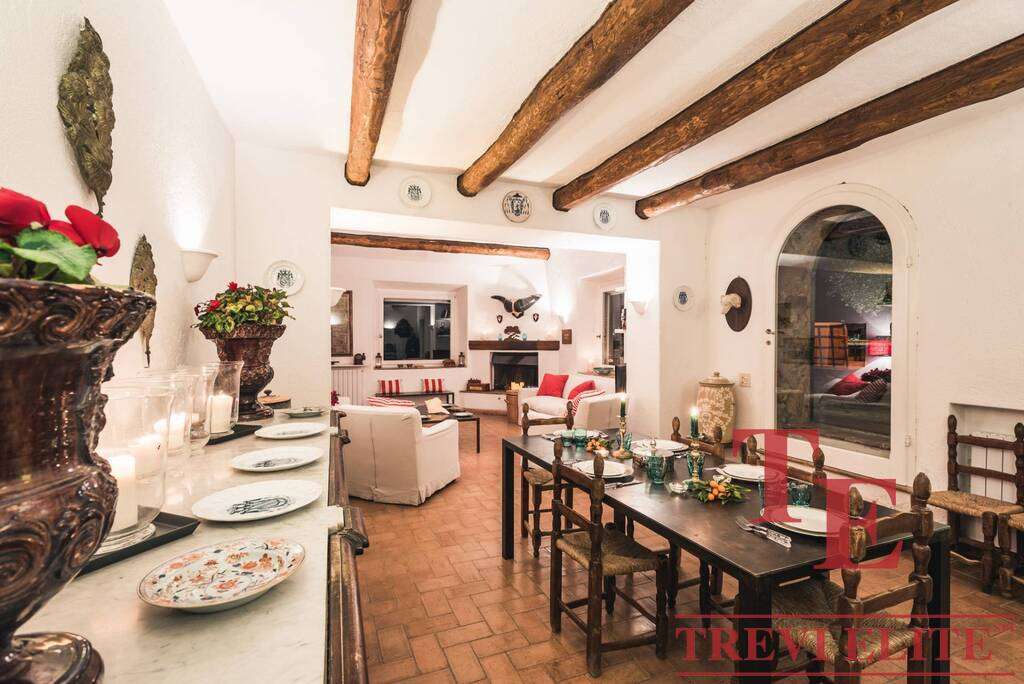 Роскошный интерьер загородного дома с белыми стенами, деревянными балками и уютной обстановкой для элитной недвижимости.