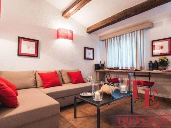 Теплая уютная гостиная с мягким диваном и красными подушками, стильной мебелью и декоративным освещением, идеально подходящая для элитной недвижимости и комфортного отдыха.