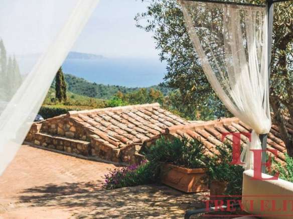 Роскошный вид на зеленые холмы и море с террасы итальянской виллы, украшенной шторками и цветами, создающий атмосферу спокойствия и уединения.