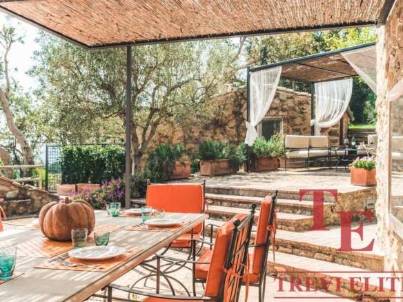 Уютный уличный обеденный уголок на террасе, окруженный зеленью и зелеными деревьями. Эргономичная мебель и декоративные элементы создают атмосферу комфорта и уединения под деревянным навесом.