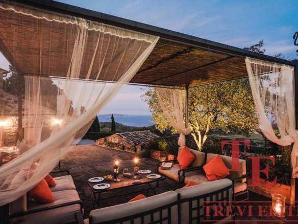 Уютная зона отдыха на открытом воздухе с видом на закат, роскошная мебель и мягкое освещение для комфортного отдыха и приема гостей.