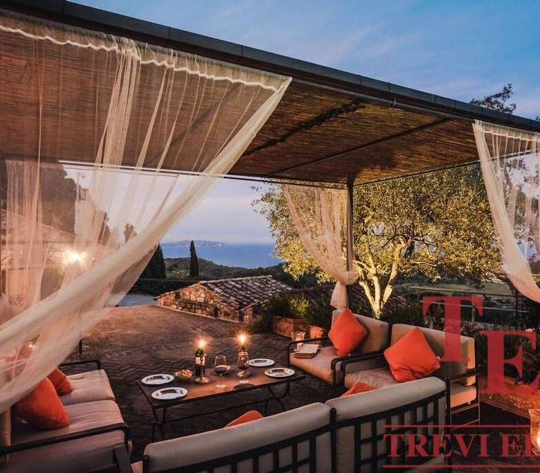 Уютная зона отдыха на открытом воздухе с видом на закат, роскошная мебель и мягкое освещение для комфортного отдыха и приема гостей.