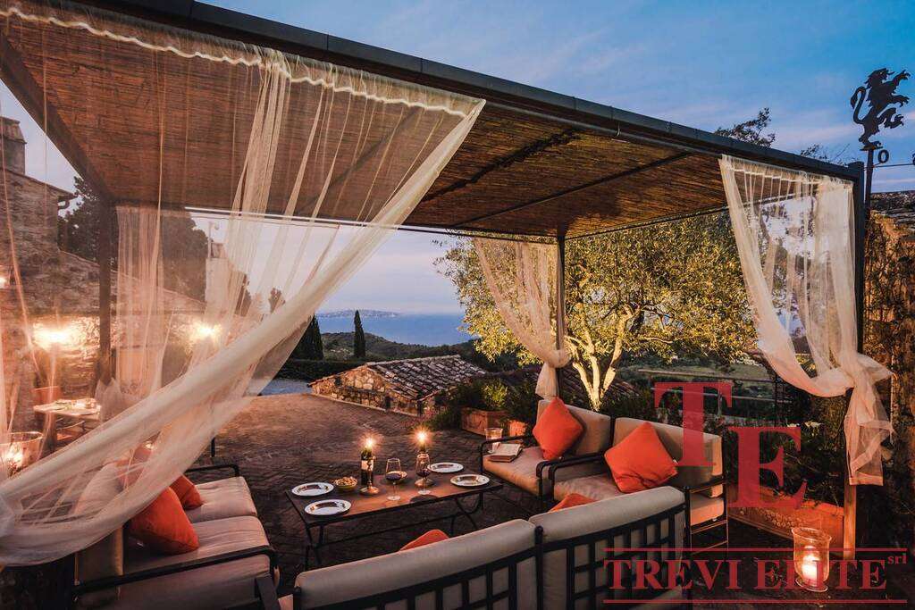 Уютная зона отдыха на открытом воздухе с видом на закат, роскошная мебель и мягкое освещение для комфортного отдыха и приема гостей.