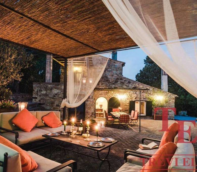 Роскошная открытая терраса с уютной мебелью и свечами, ночная подсветка, стильный дизайн, идеальный для вечерних мероприятий и отдыха на загородной вилле.