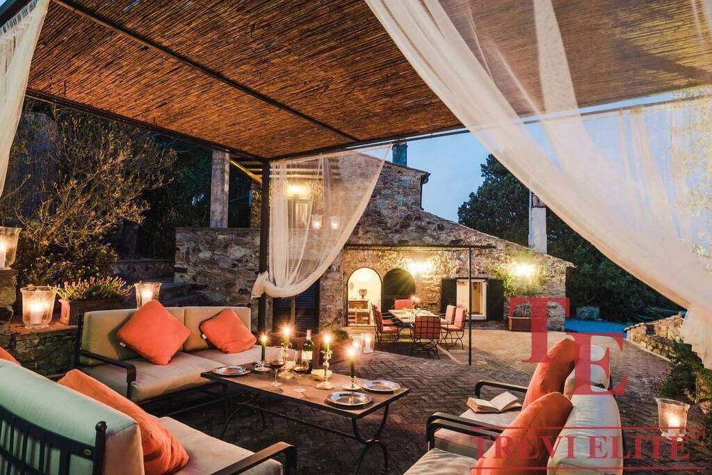Роскошная открытая терраса с уютной мебелью и свечами, ночная подсветка, стильный дизайн, идеальный для вечерних мероприятий и отдыха на загородной вилле.