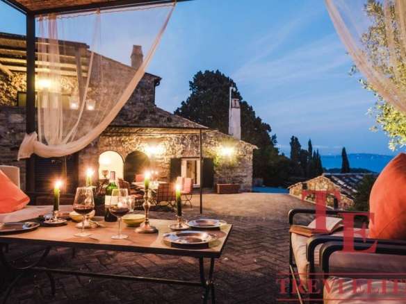 Элегантная веранда на закате с уютной зоной отдыха, свечами и видом на природу, идеально подходит для роскошных мероприятий и расслабления в элитной недвижимости.