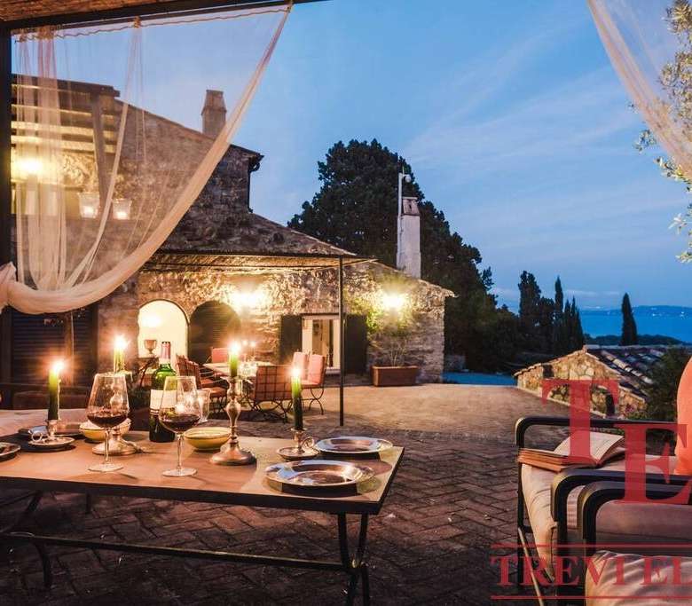 Элегантная веранда на закате с уютной зоной отдыха, свечами и видом на природу, идеально подходит для роскошных мероприятий и расслабления в элитной недвижимости.