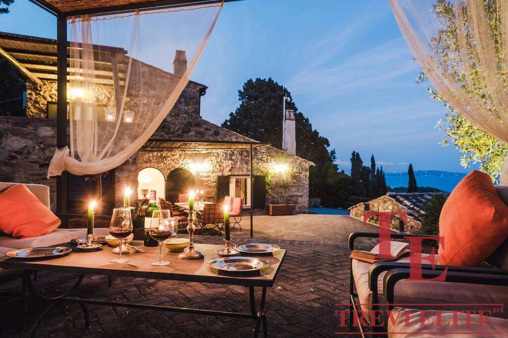 Элегантная веранда на закате с уютной зоной отдыха, свечами и видом на природу, идеально подходит для роскошных мероприятий и расслабления в элитной недвижимости.