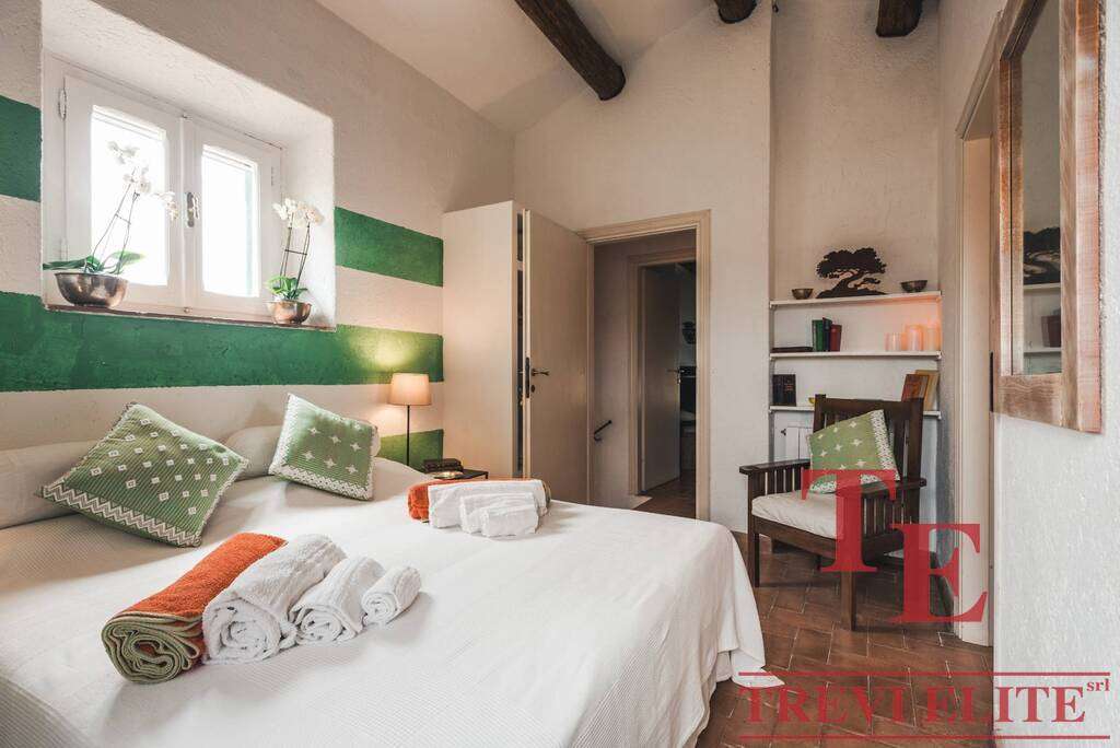 Элитная спальня в роскошной итальянской недвижимости, уютная и стильная, с зелеными акцентами, мягкой мебелью и современным декором, идеально подходит для комфортного проживания.