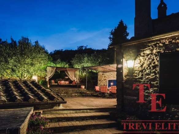 Уединённый уютный дворик у роскошной загородной недвижимости с мягким освещением и зоной отдыха на свежем воздухе. Отличное место для вечерних мероприятий и расслабления в окружении природы.