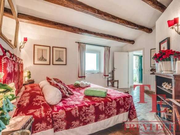 Роскошная спальня с деревянными потолочными балками, ярким уютным декором и крупной кроватью в классическом стиле, с видом на светлое окно и уютной атмосфрой для высокого комфорта проживания.