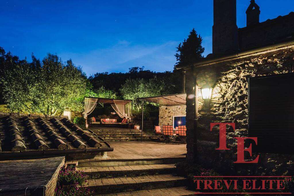 Уединённый уютный дворик у роскошной загородной недвижимости с мягким освещением и зоной отдыха на свежем воздухе. Отличное место для вечерних мероприятий и расслабления в окружении природы.