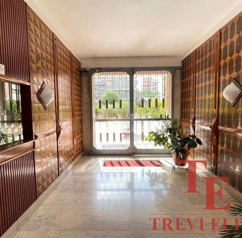 Элегантный интерьер входной зоны с деревянными панелями, большими окнами и комнатными растениями, создающими уютную атмосферу в роскошной недвижимости.