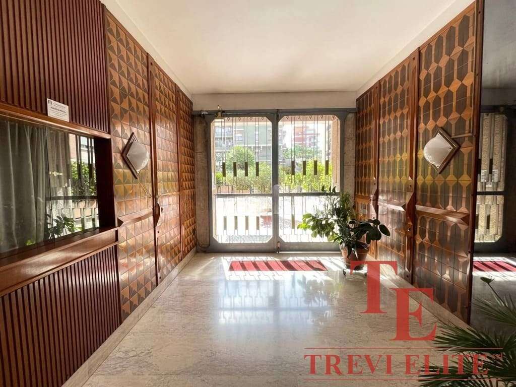 Элегантный интерьер входной зоны с деревянными панелями, большими окнами и комнатными растениями, создающими уютную атмосферу в роскошной недвижимости.