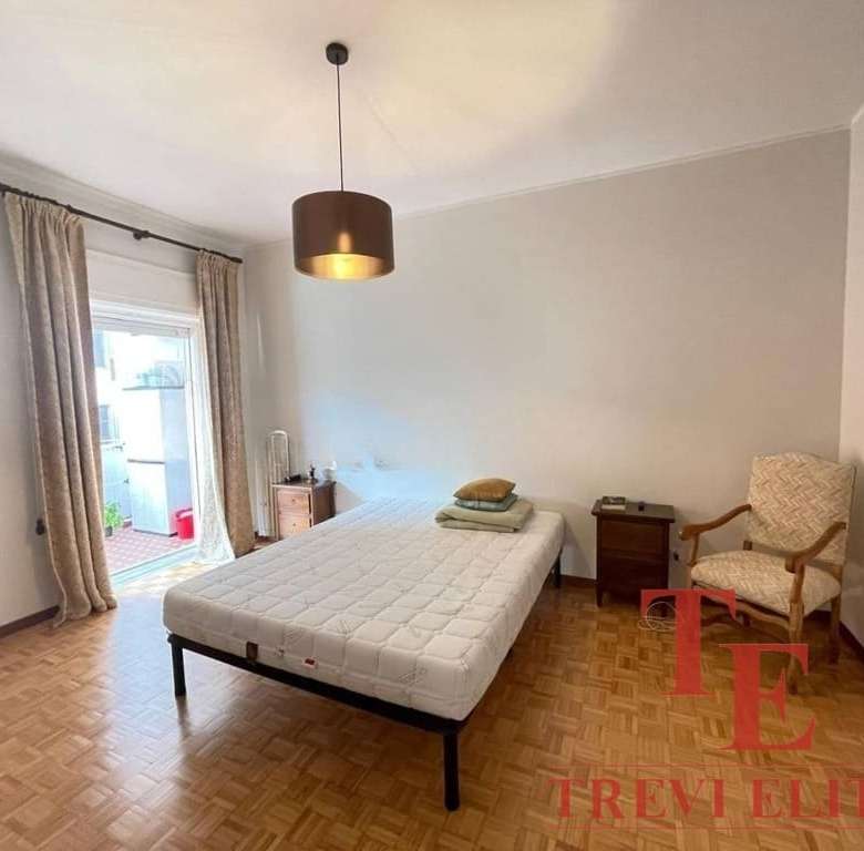 Современная спальня с выходом на балкон, светлые стены, деревянный паркет, уютная мебель и комфортная атмосфера для отдыха. Идеальное жилье в престижном районе с видом на город.