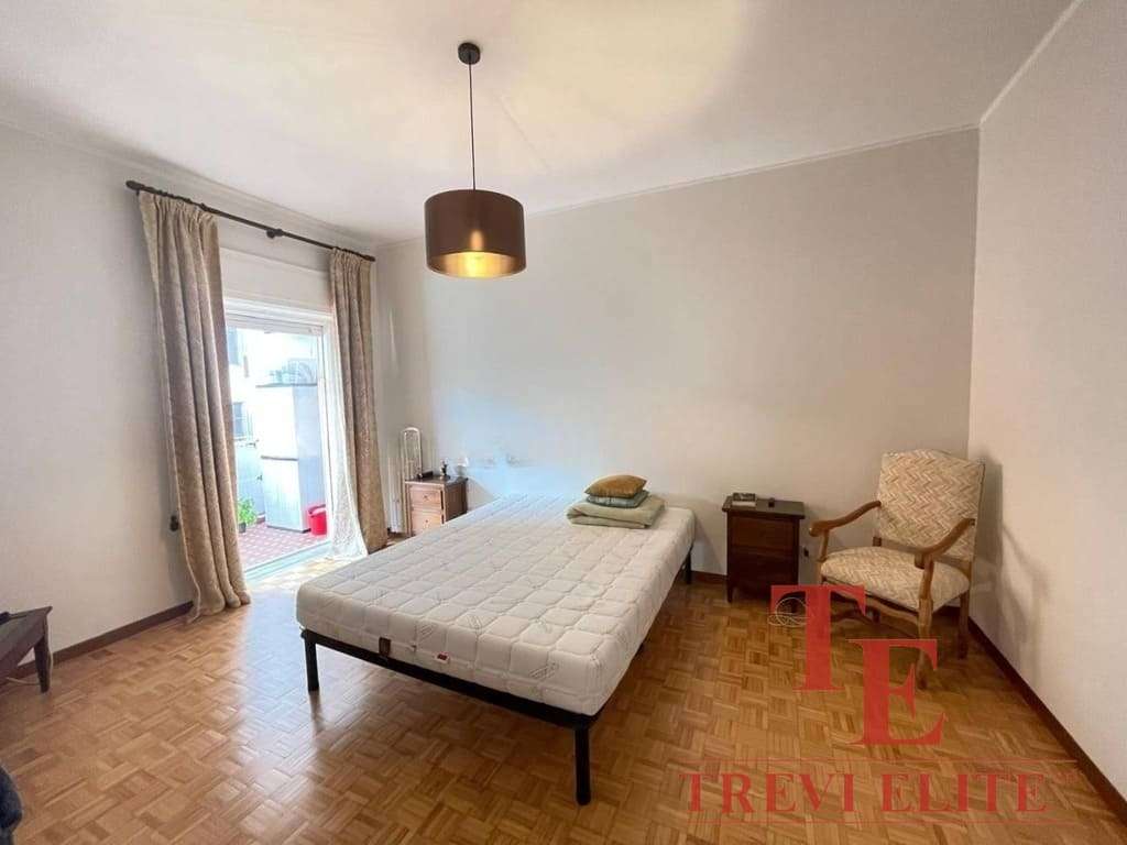 Современная спальня с выходом на балкон, светлые стены, деревянный паркет, уютная мебель и комфортная атмосфера для отдыха. Идеальное жилье в престижном районе с видом на город.