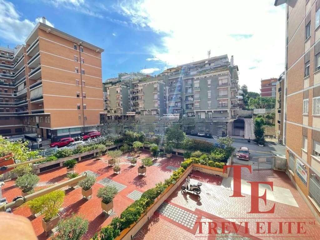 Уютный двор с зеленой зоной и пешеходной дорожкой в жилом комплексе, окруженном современными многоэтажками в центре города.