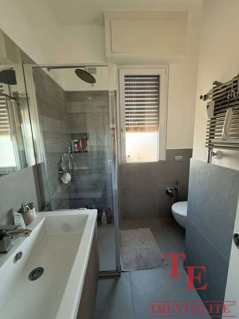 Современная ванная комната с душевой кабиной, раковиной и окном с ролл-шторами, выполненная в стильных нейтральных оттенках, идеально подходит для роскошной жизни.