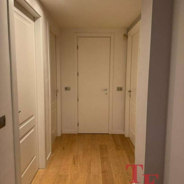 Элегантная прихожая с белыми стенами и деревянным полом в роскошном доме, созданная для высокого стиля и комфорта.