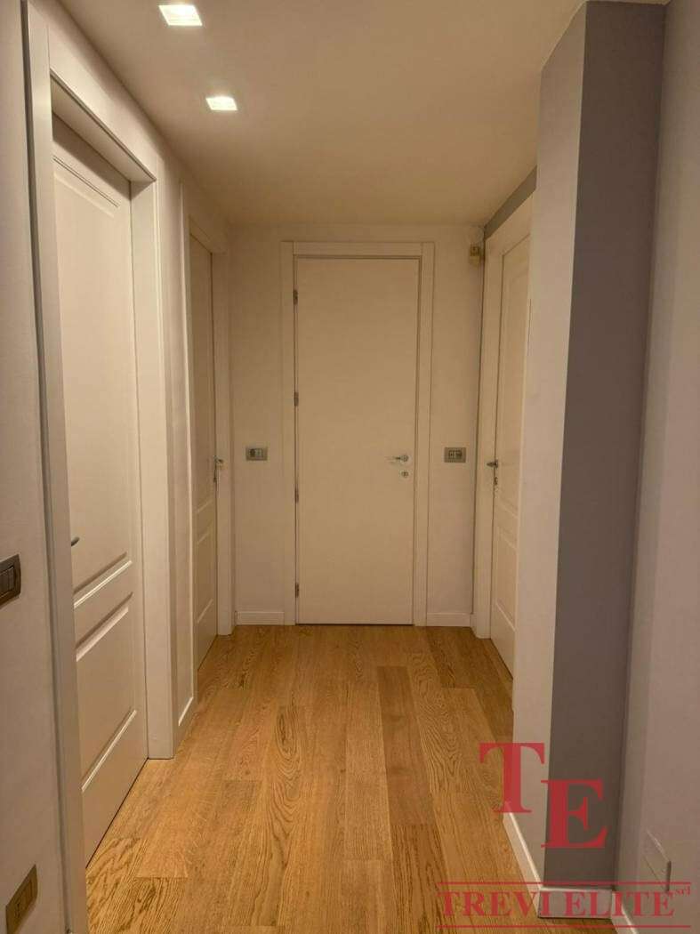 Элегантная прихожая с белыми стенами и деревянным полом в роскошном доме, созданная для высокого стиля и комфорта.