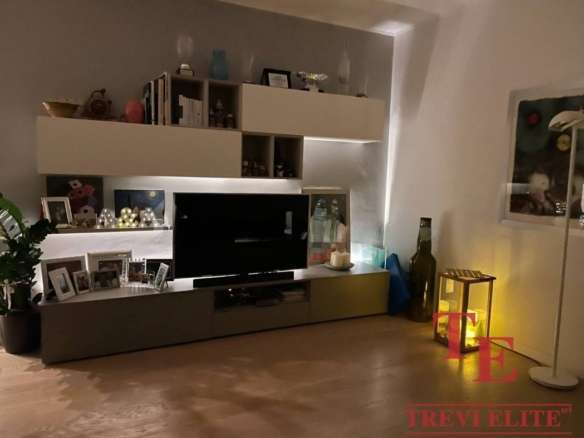 Современная гостиная с телевизором, декоративными элементами и теплым освещением для роскошной жизни.